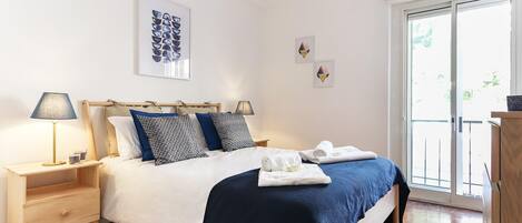 A bedroom with a bed, bedside tables, a lamp, and artwork on the wall.