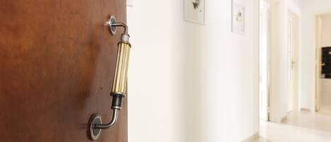 A wooden door with a modern handle and a hallway with white walls and framed pictures.