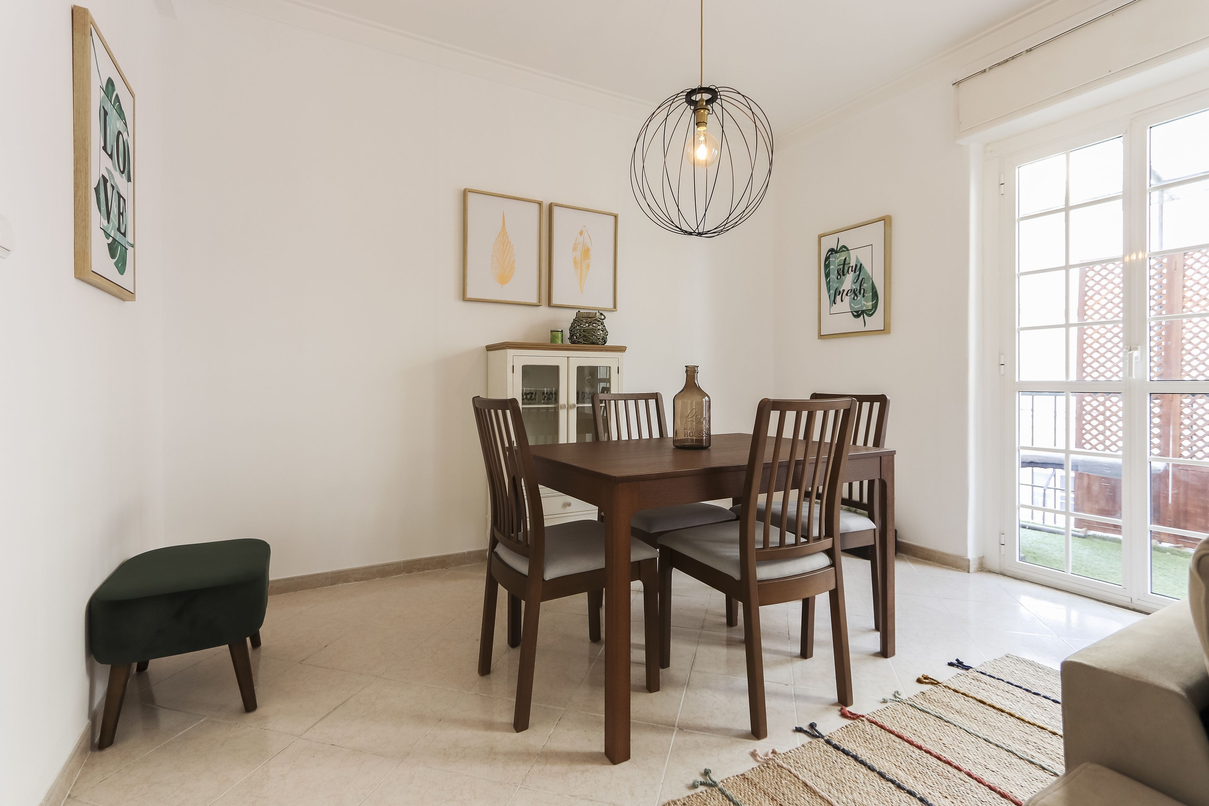 Un coin repas avec une table et des chaises en bois, un buffet avec des portes en verre et un luminaire suspendu.