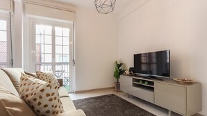 A living room with a sofa, TV, and a plant. - Principe Real Balcony by Homing (Lisbon)