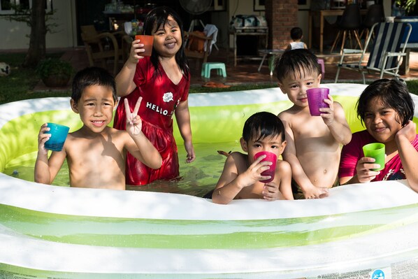 Children playing in a small inflatable pool with a warning label. - Phuttal Residence (Ayutthaya)