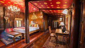A traditional wooden room with a bed, a table, and a chandelier. - Phuttal Residence (Ayutthaya)