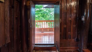 A wooden interior with a view of a wooden deck and lush greenery outside. - Phuttal Residence (Ayutthaya)