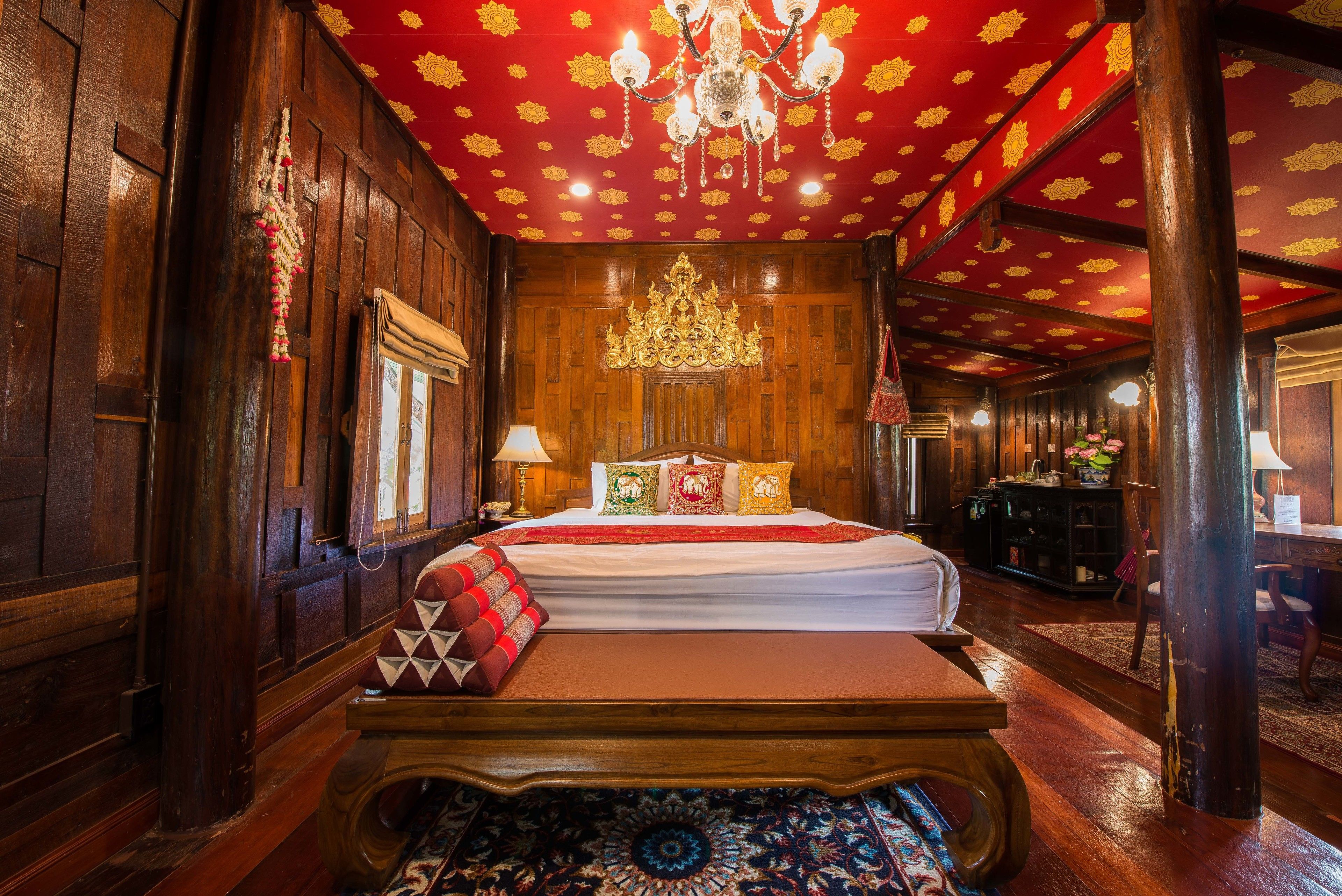 A traditional wooden room with a large bed, ornate ceiling, and a chandelier.