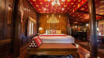 A traditional wooden room with a large bed, ornate ceiling, and a chandelier.