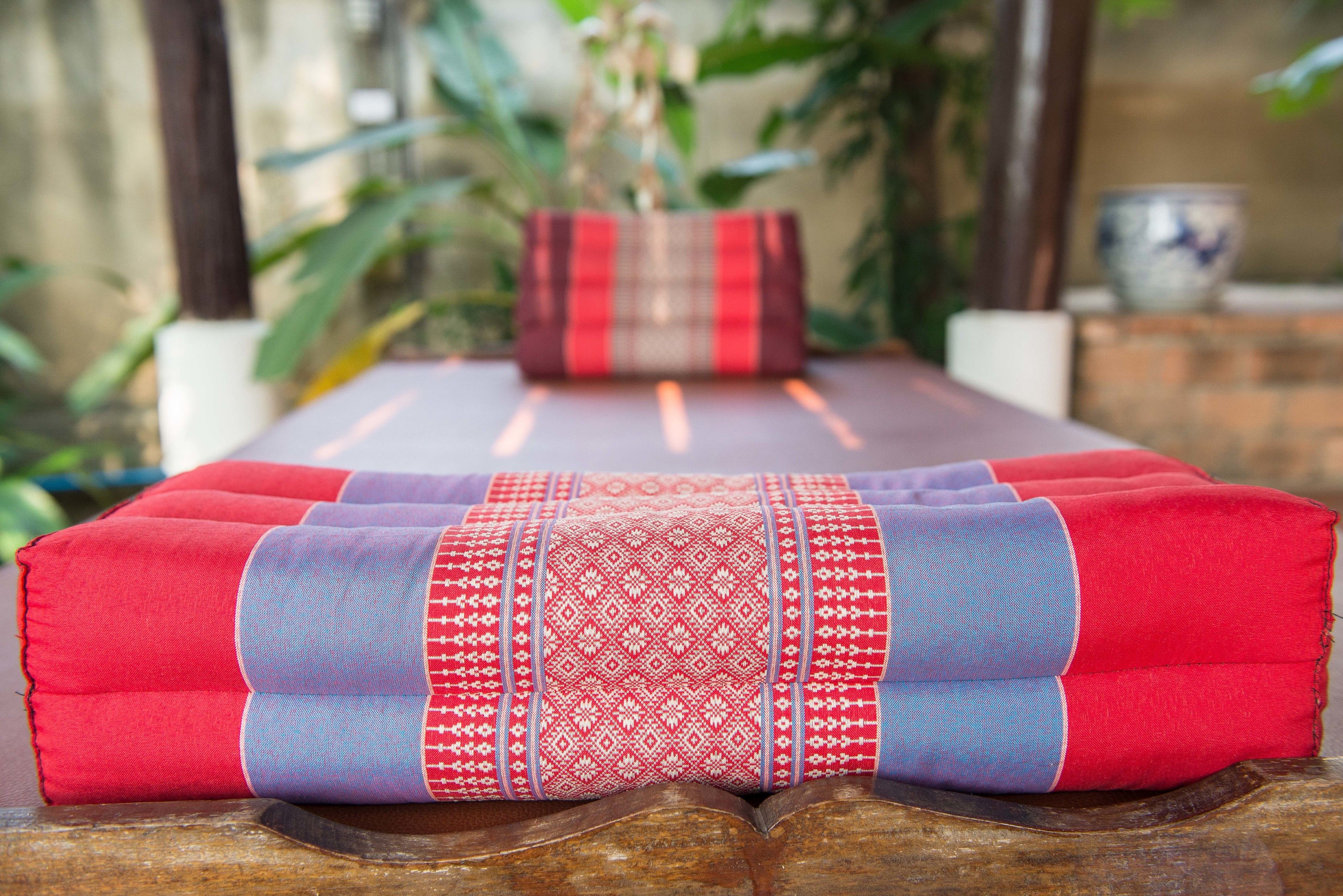 Une table de massage avec un coussin à motifs rouges et bleus.