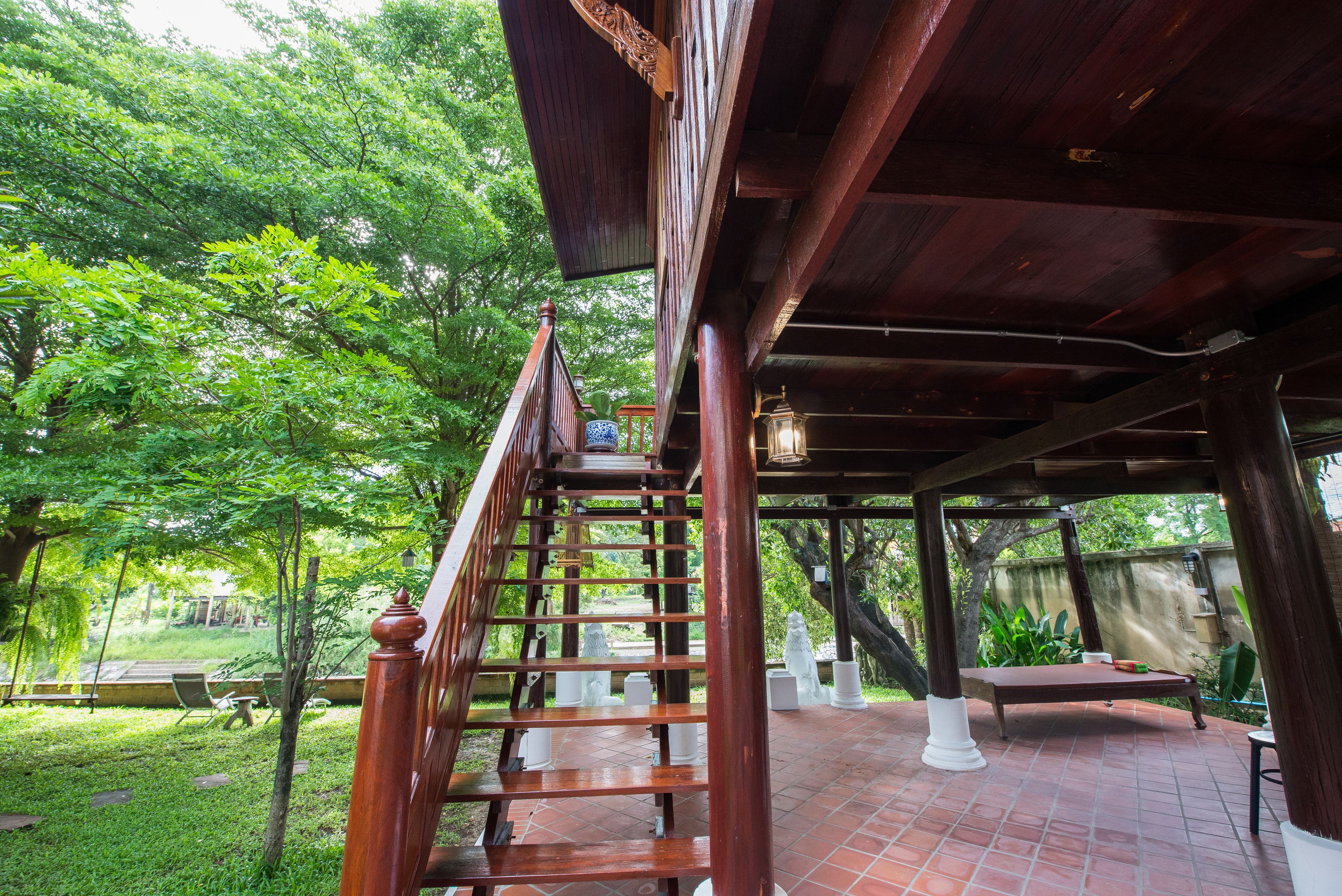 A wooden staircase leading to a covered area with a bench and potted plants.