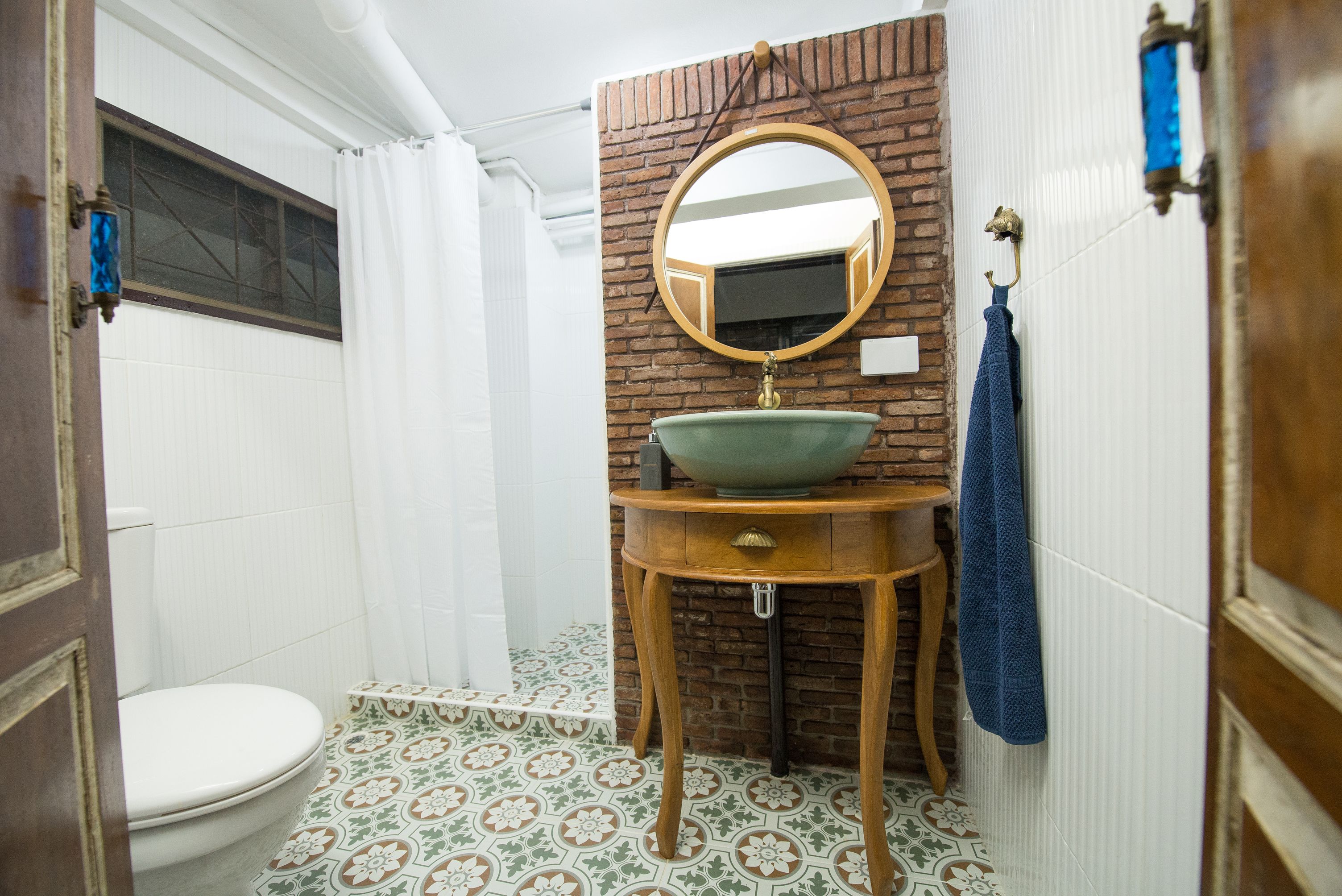 Un baño con inodoro, lavamanos con espejo y una toalla azul colgada en la pared.