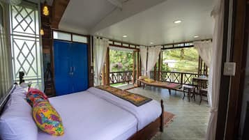 Un dormitorio con una cama grande, un cabecero de madera y vistas a una terraza exterior con una mesa y sillas.