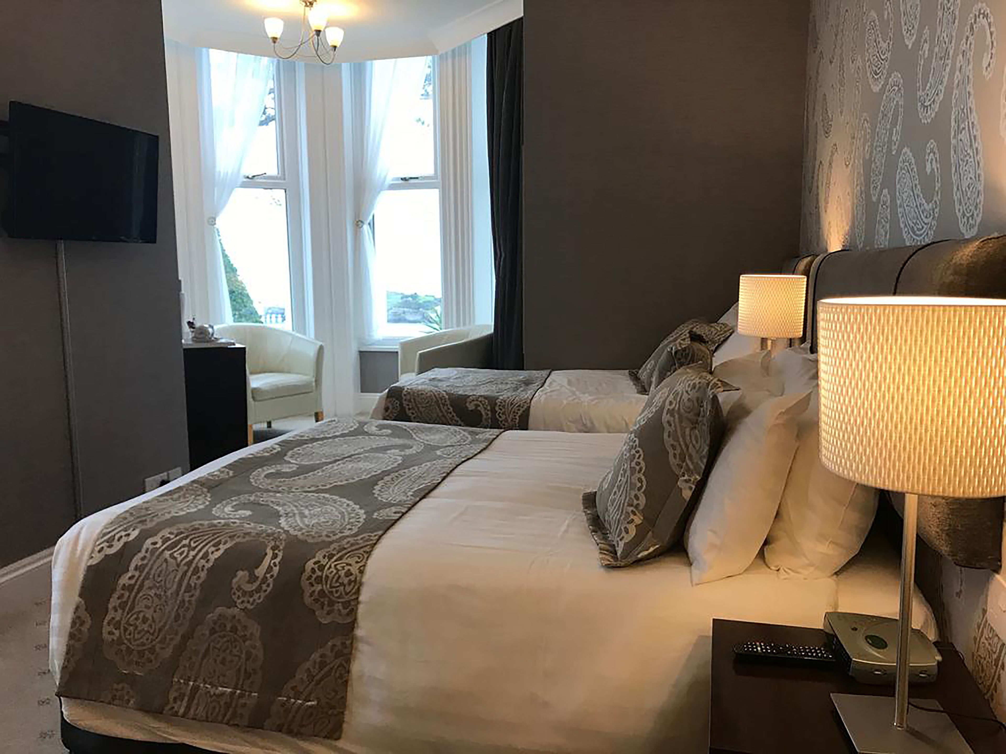 Ein Hotelzimmer mit einem großen Bett, zwei Nachttischlampen, einem Fernseher und einem Sessel.