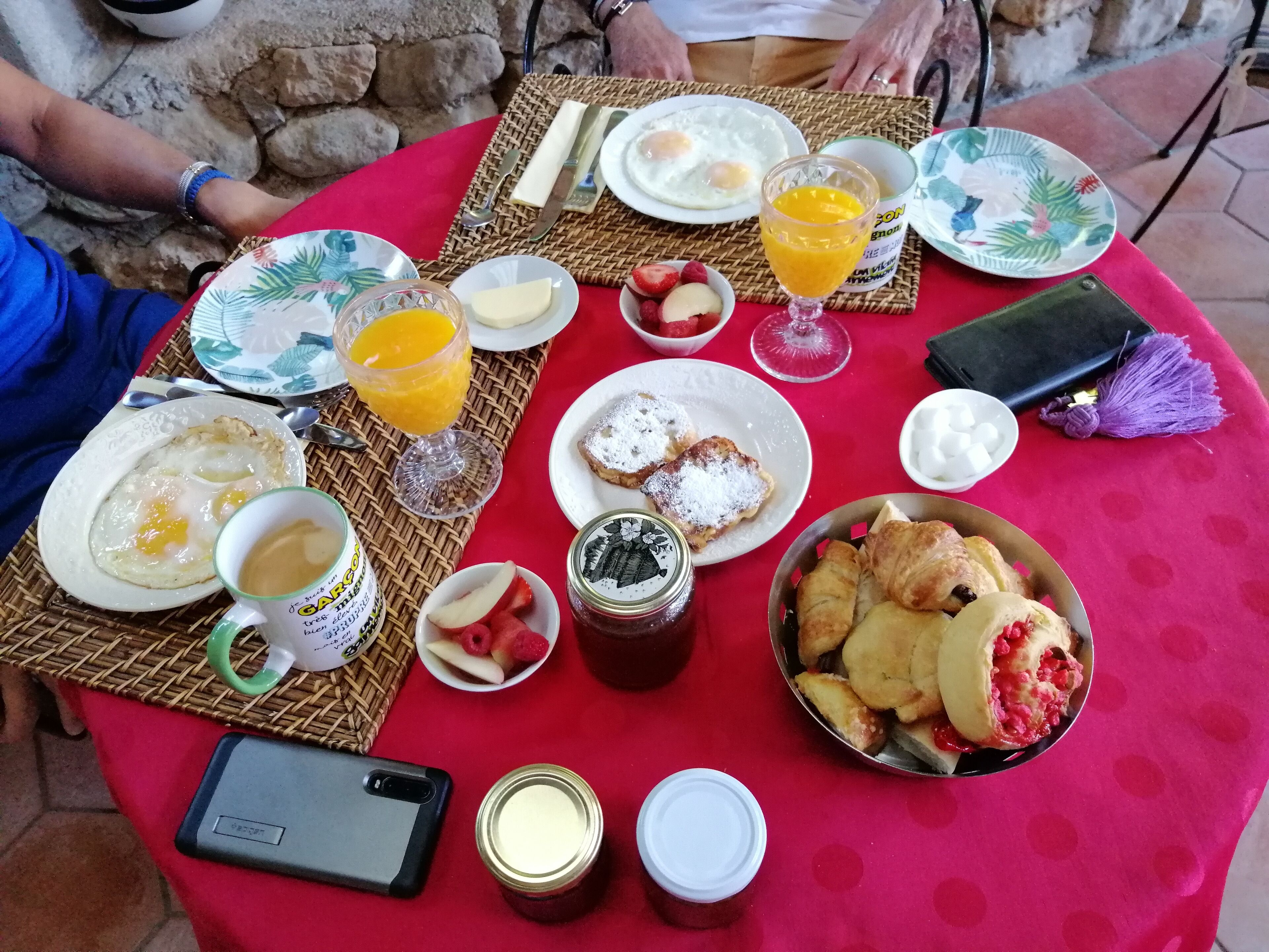 Una mesa de desayuno con huevos, tostadas, fruta y bebidas.