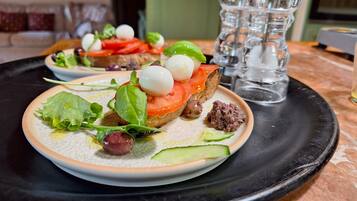 En tallrik med en sallad, ett glas vatten och en saltströare på ett bord.