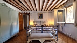 Un dormitorio con cama, banco, armario y ventana.