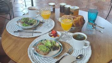Un desayuno servido con platos de comida, una taza de café y un vaso de jugo de naranja sobre una mesa redonda.