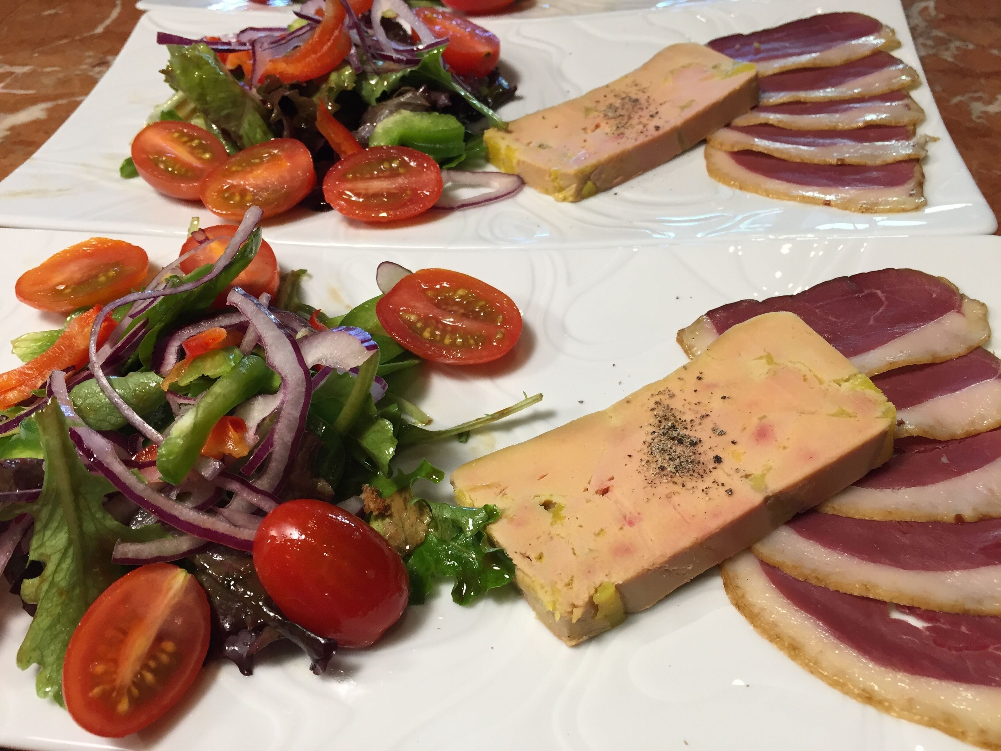 A plate with a variety of food including a salad, tomatoes, and slices of meat.