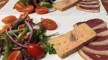 A plate with a variety of food including a salad, tomatoes, and slices of meat.