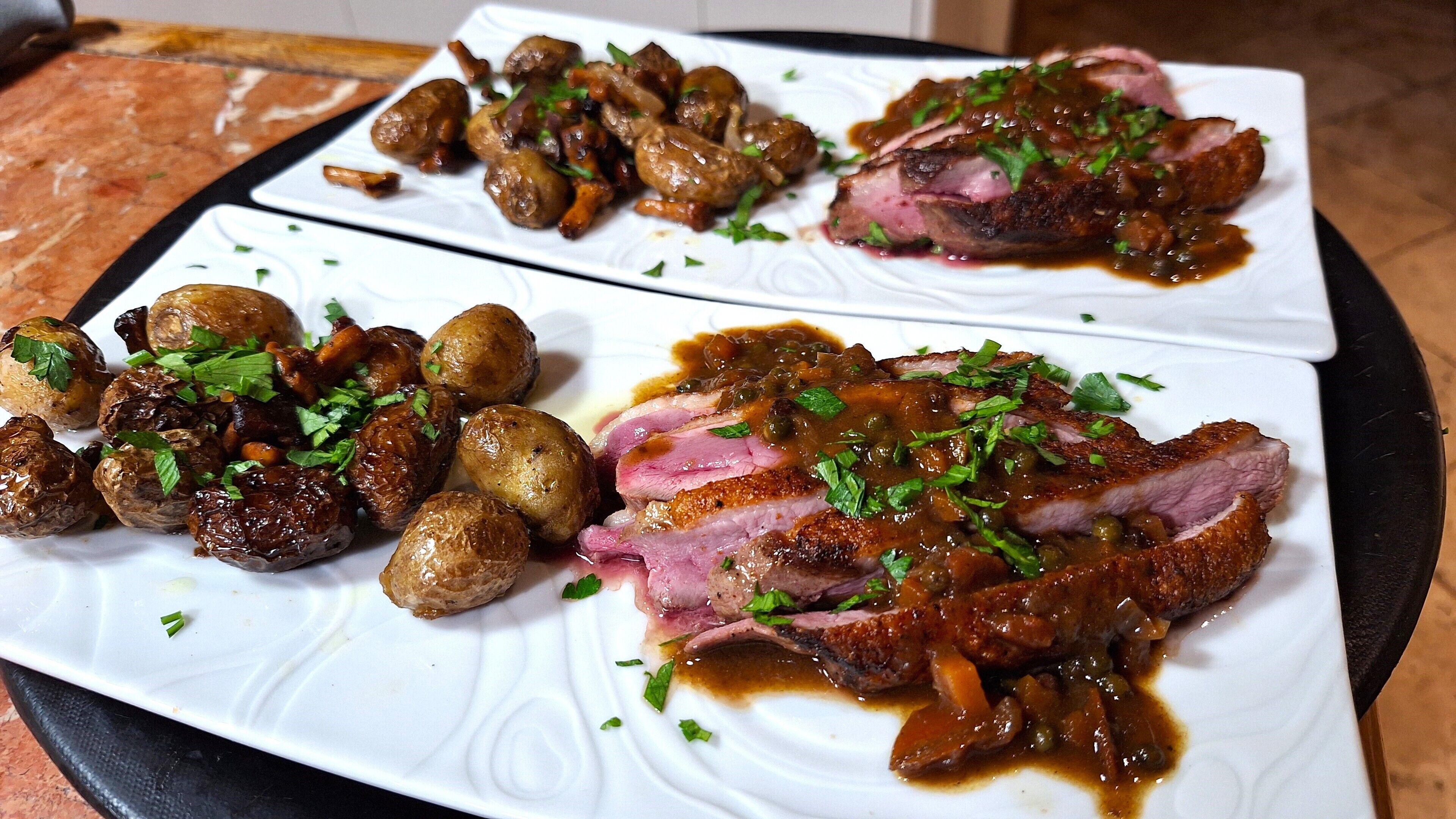 Un plato con patatas asadas, una porción de carne y salsa.
