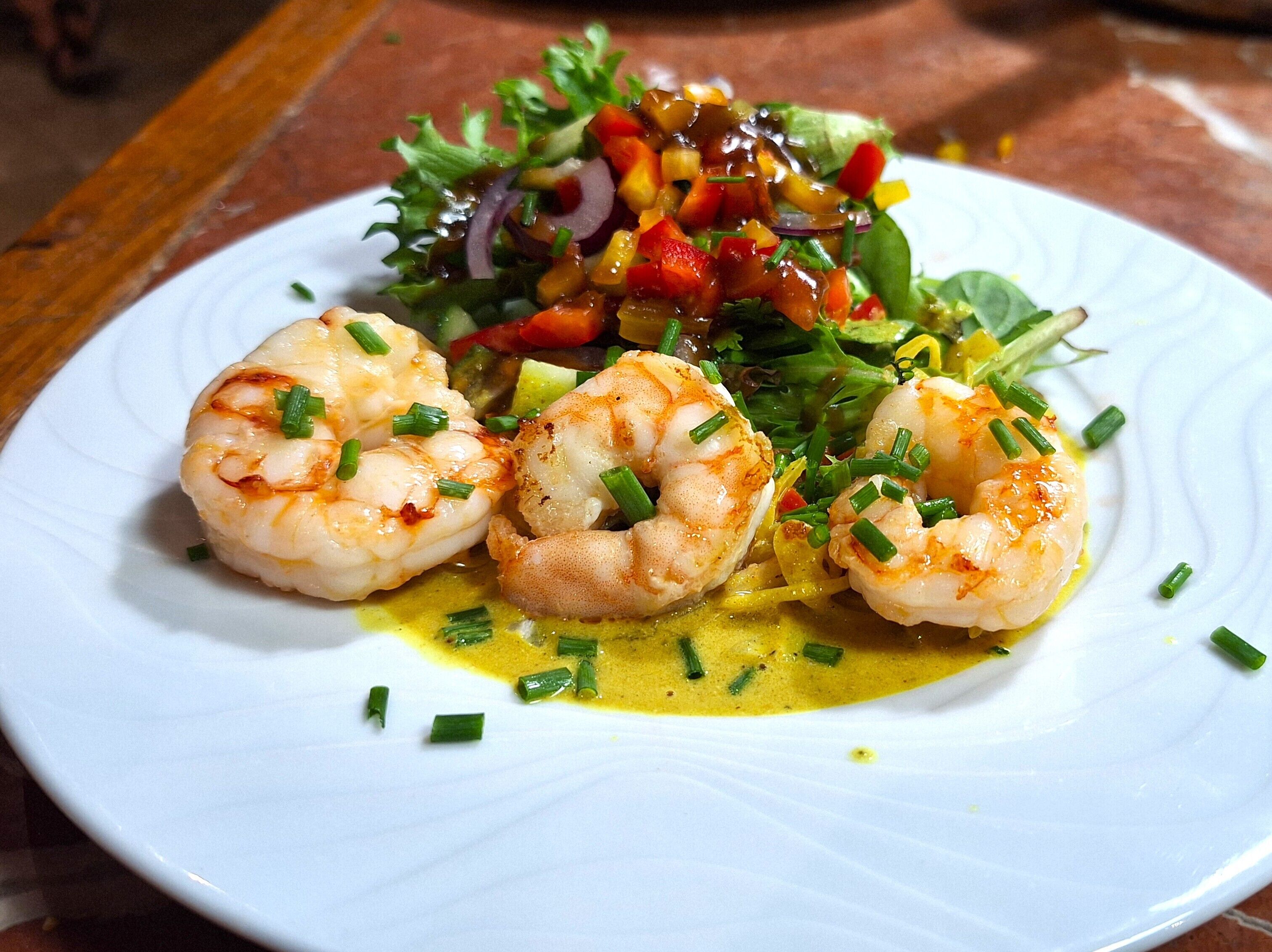 Un plato de camarones con ensalada y salsa cremosa.