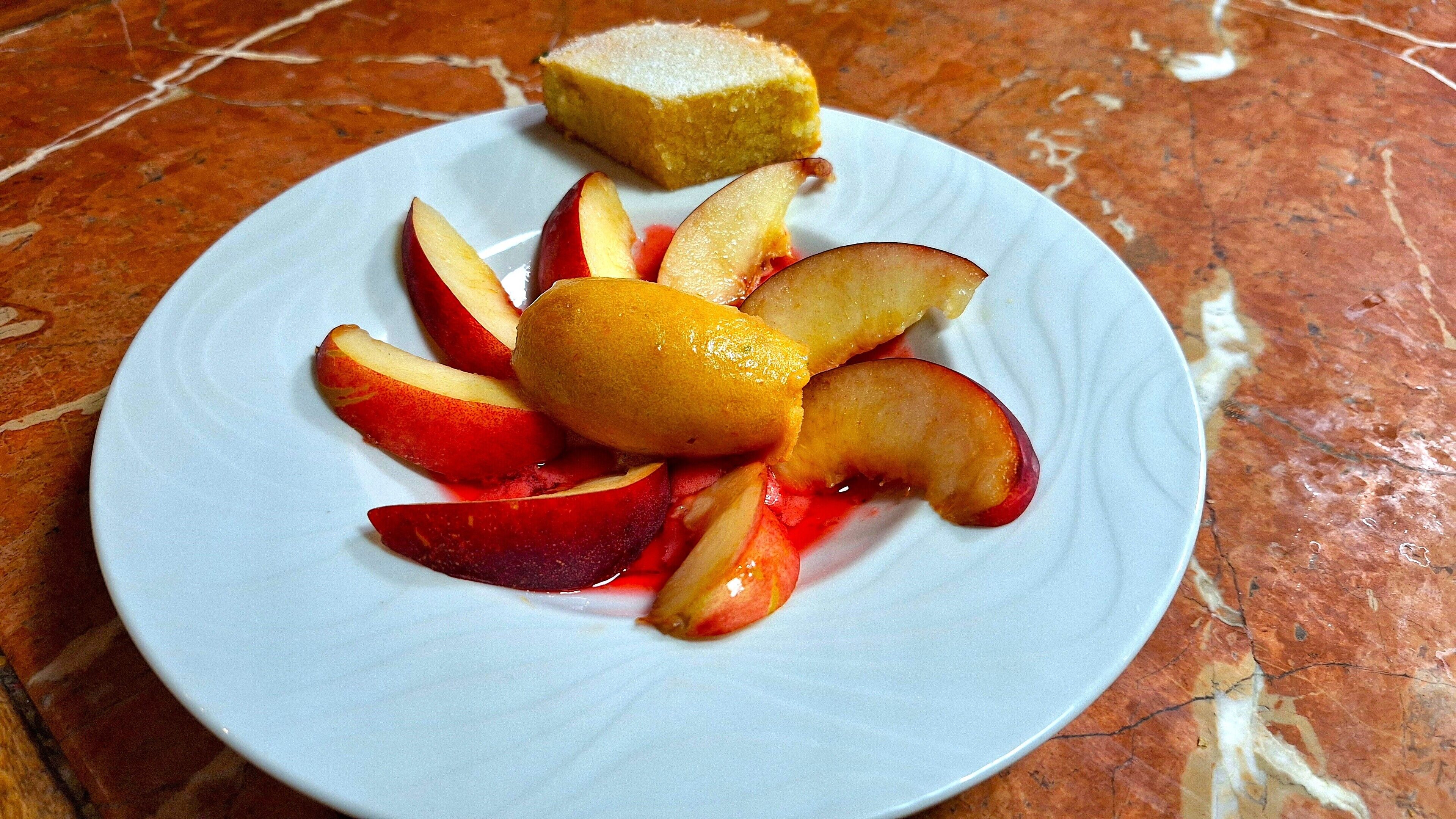 Un plato con rodajas de manzana y un trozo de pastel sobre una superficie de mármol.