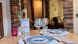 Una mesa de comedor preparada con platos, vasos y una carta.