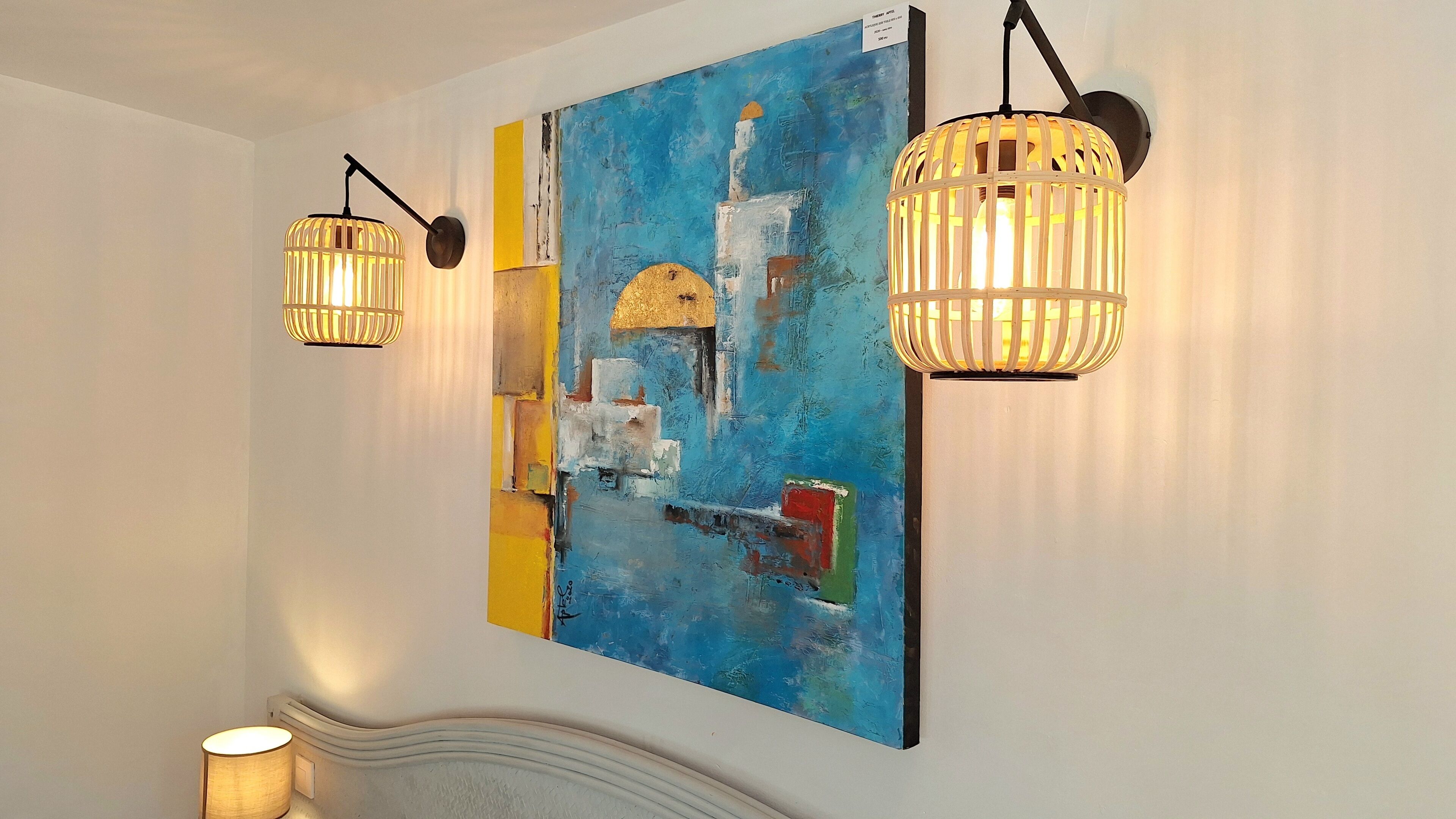 A hallway with two wall-mounted pendant lights and a large abstract painting.
