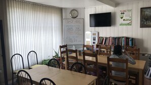 Un comedor con un menú en pizarra, un reloj y una estantería.