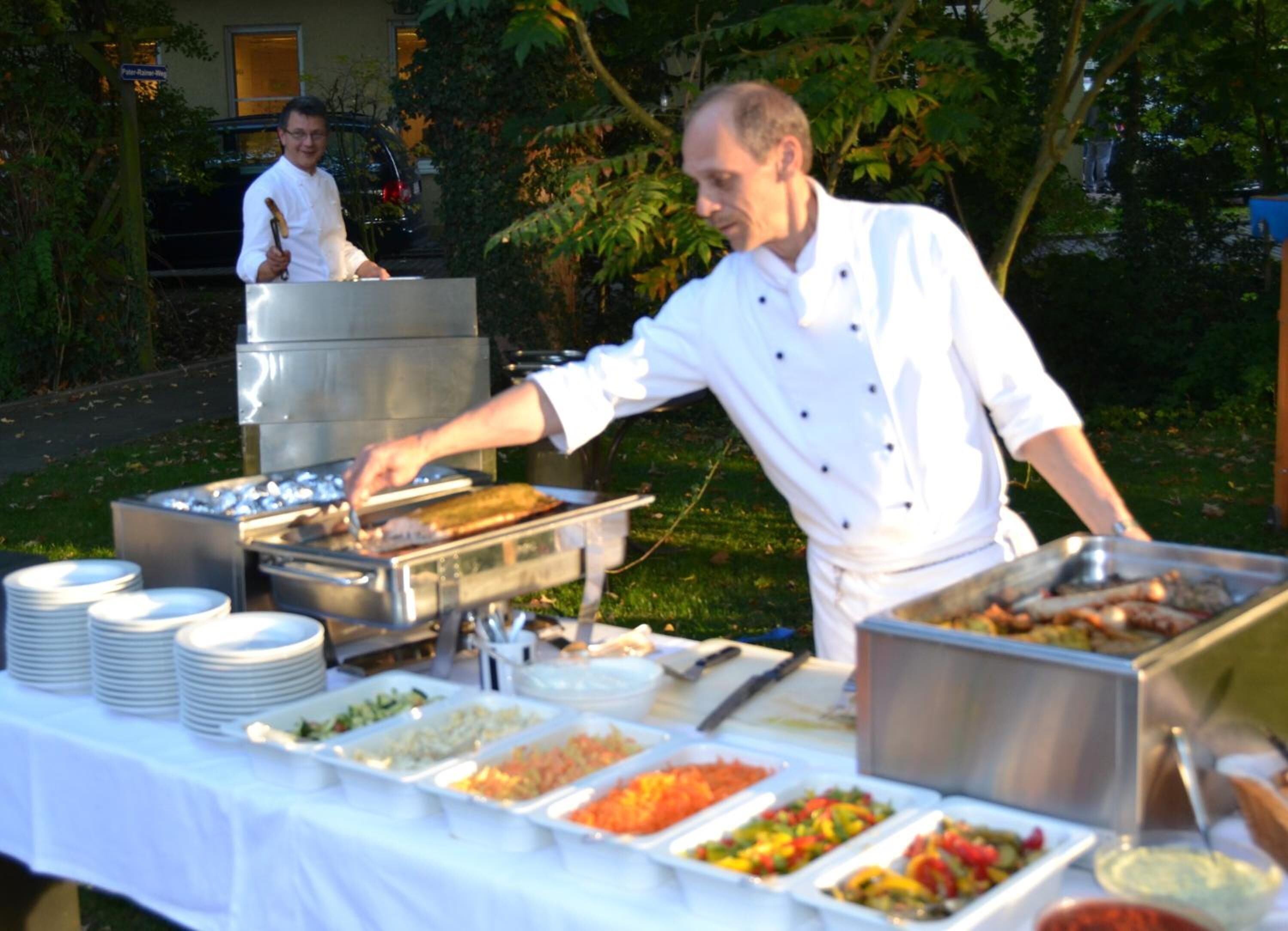 Een buffetopstelling met diverse gerechten en een kok die serveert.