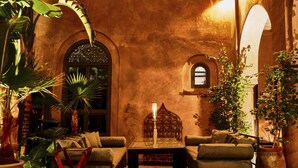 A cozy lounge area with a sofa set, a table with a candle, and tropical plants. - Riad Noir d'Ivoire (Marrakech)