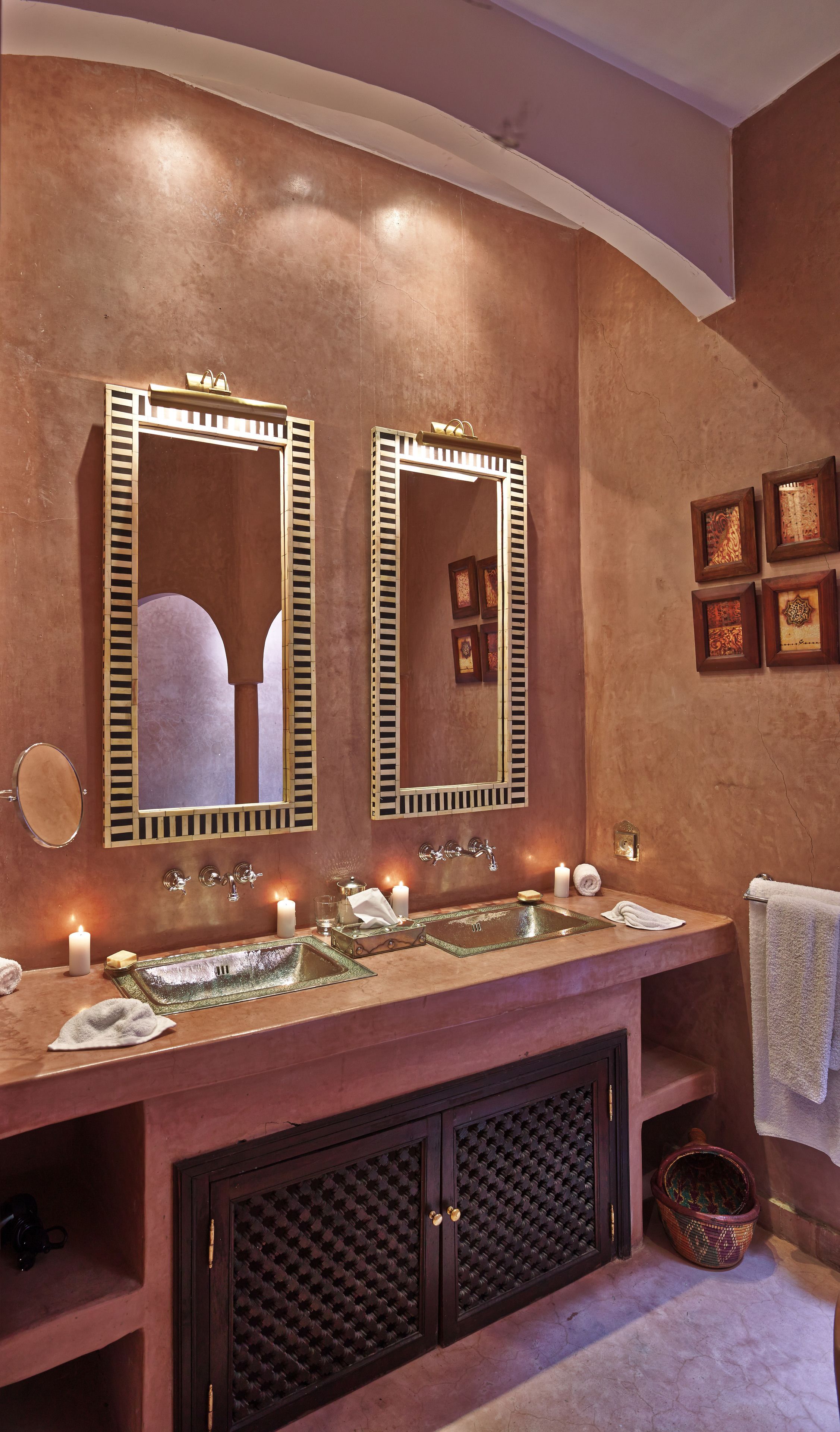 A bathroom with a double vanity, two mirrors, a sink with a glass top, a towel rack, and a decorative basket.