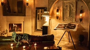 A cozy room with a fireplace, a sofa, a table with candles, and a painting. - Riad Noir d'Ivoire (Marrakech)
