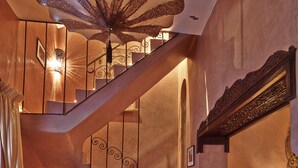 A grand staircase with ornate railings and a chandelier, leading to a second floor. - Riad Noir d'Ivoire (Marrakech)