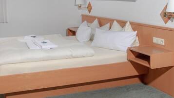 Una habitación de hotel con una cama, una mesita de noche y una lámpara de pared.