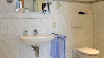 Un baño con lavamanos, espejo e inodoro.