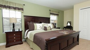 A bedroom with a large bed, a nightstand, a dresser, and a door. - Grhmyr1465 - Champions Gate Resort - 6 Bed 6 Baths House (Davenport)