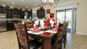 A dining area with a wooden table set for six, surrounded by dark wooden chairs. - Grhmyr1465 - Champions Gate Resort - 6 Bed 6 Baths House (Davenport)