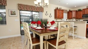 Un coin repas avec une table en bois dressée pour six personnes, entourée de chaises de couleur beige.