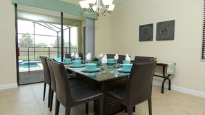 A dining area with a glass table set for four, surrounded by chairs. - Grhmvd1494 - Champions Gate Resort - 5 Bed 4 Baths House (Davenport)