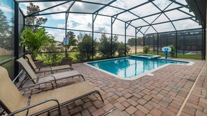 An indoor swimming pool with a glass enclosure, surrounded by lounge chairs and potted plants. - Grhmvd1494 - Champions Gate Resort - 5 Bed 4 Baths House (Davenport)