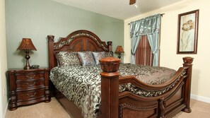 A bedroom with a wooden four-poster bed, a nightstand with a lamp, and a dresser.