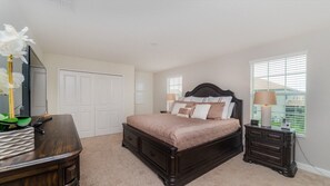 A bedroom with a large bed, a dresser, a nightstand, and a window with blinds. - Grhmvd1534 - Champions Gate Resort - 6 Bed 6 Baths House (Davenport)