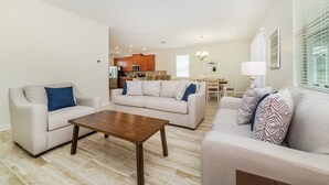 A spacious living room with two sofas, a coffee table, and a dining area in the background. - Grhmvd1554 - Champions Gate Resort - 5 Bed 4 Baths House (Davenport)