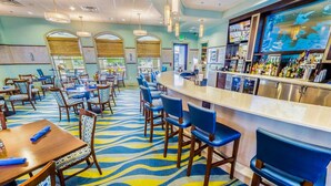 A hotel lobby with a bar area, multiple seating arrangements, and a patterned carpet.