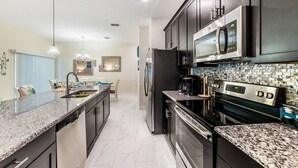A modern kitchen with granite countertops, stainless steel appliances, and a tiled backsplash.