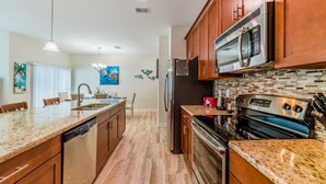 A modern kitchen with granite countertops, stainless steel appliances, and wooden cabinets.