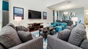 Ein modernes Wohnzimmer mit grauen Sofas, einem Couchtisch, einem Fernseher und Kunstwerken an den Wänden.