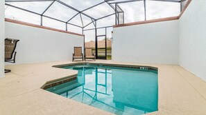 An indoor swimming pool with a glass ceiling, two chairs, and a view of a brick wall outside. - Grhmvd1596 - Champions Gate Resort - 5 Bed 4 Baths Townhouse (Davenport)