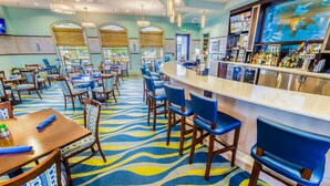Un restaurant doté d’un bar, de plusieurs tables et chaises, et d’un tapis à motifs.