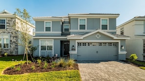 A two-story house with a stone facade, a garage, and a well-maintained lawn. - Grhmvd1688 - Champions Gate Resort - 6 Bed 6 Baths House (Davenport)