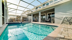 An indoor swimming pool with clear water, surrounded by lounge chairs and a covered patio area. - Grhmvd1688 - Champions Gate Resort - 6 Bed 6 Baths House (Davenport)