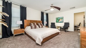 A bedroom with a large bed, a nightstand, a desk, a chair, and a ceiling fan. - Grhmvd1688 - Champions Gate Resort - 6 Bed 6 Baths House (Davenport)